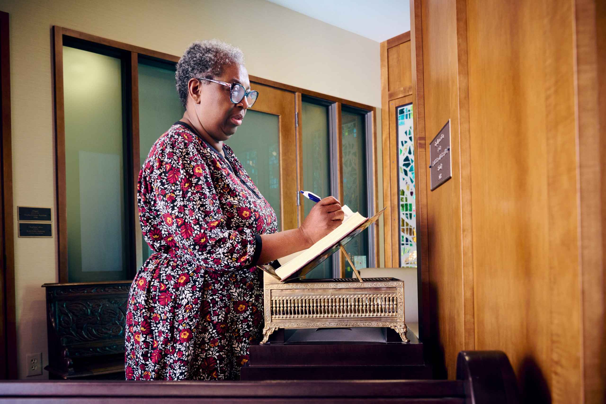 An individual adds their thoughts to a prayer book, contributing to a collective source of strength and support for all who visit the chapel at Shepherd Center.